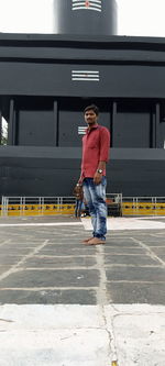 Full length of man standing on sidewalk in city