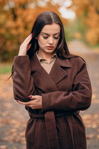 Young beautiful woman in brown coat in the park in autumn