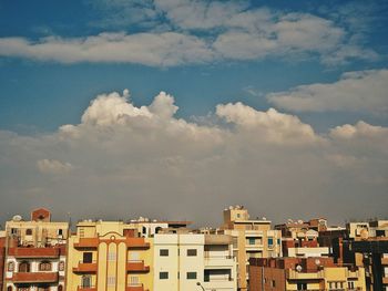 Buildings in town against cloudy sky