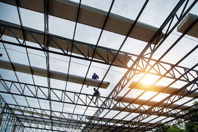 Asian construction workers are installing metal roofing sheets for industrial roof installations.