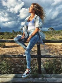 Full length of woman looking away against sky