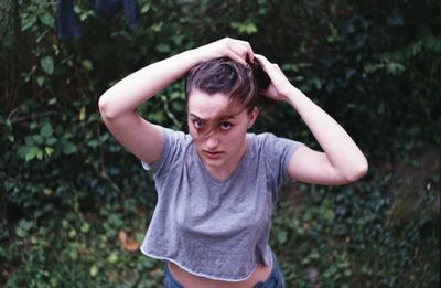 High angle portrait of young woman tying up hair