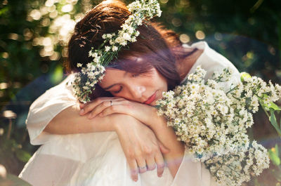 Mid adult woman with white flowers napping in forest