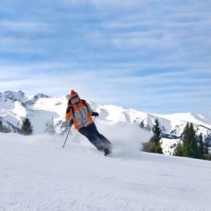 Man skiing on snow covered mountain against sky