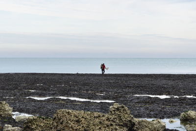 Man standing at beach against sky