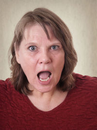 Close-up portrait of woman shouting against wall