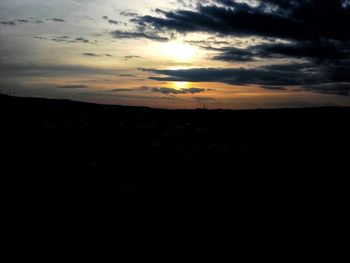 Silhouette landscape against dramatic sky during sunset