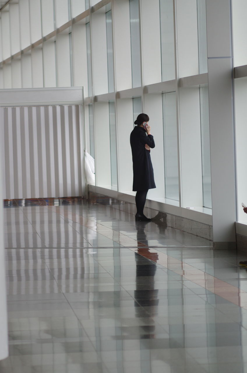 SIDE VIEW OF WOMAN WALKING IN CORRIDOR OF BUILDING