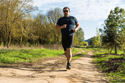 Overweight young man jogging in the park. weight loss concept. big belly male running, doing cardio 