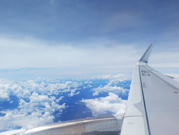 Aerial view of airplane flying over clouds against blue sky