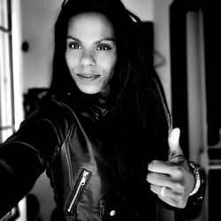 Portrait of woman gesturing thumbs up while standing at home