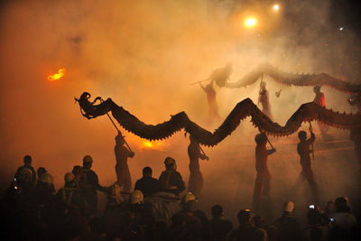 Silhouette of people at music concert against sky during sunset