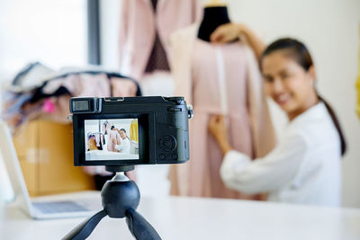 Close-up of camera photographing female fashion designer with mannequin in office