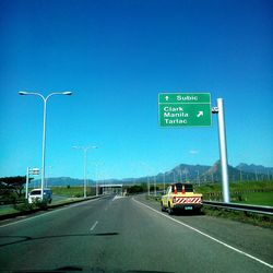 Road sign on highway against sky