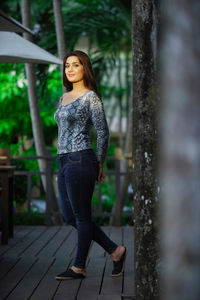 Portrait of young woman standing against trees