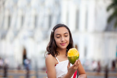 Girl eating mango at the ortiz bridge with la ermita church on background in the city of cali