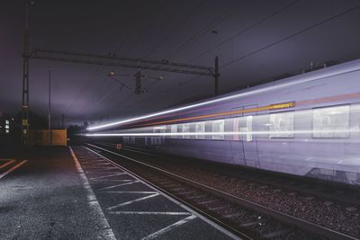 Railroad tracks against sky at night