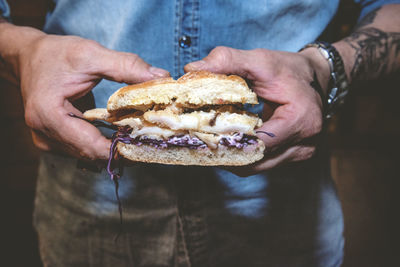 Midsection of man holding a sandwich