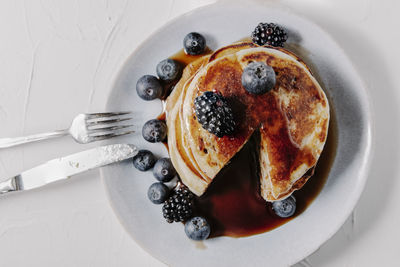 A stack of pancakes with berries and syrup