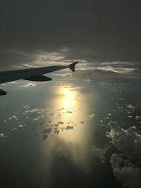 Airplane flying over sea against sky during sunset