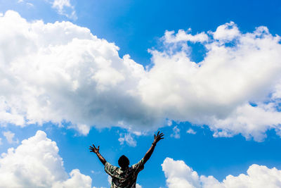 Low angle view of man with arms raised against sky