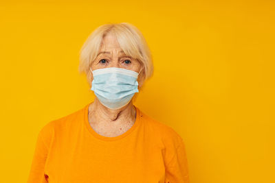 Portrait of man wearing protective mask against yellow background