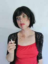 Injured woman holding cigarette against white background