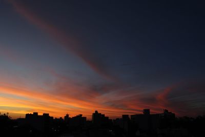 Silhouette cityscape against sky at night