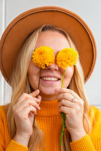 Close-up of young woman holding flower against white background