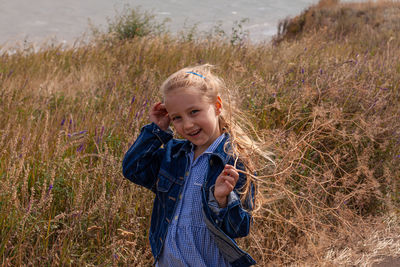 Blond long hair child girl in denim jacket walks on sea landscape. travelling hiking running outdoor