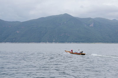 Man on boat in sea against mountains