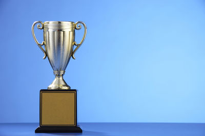 Close-up of trophy on table against blue background