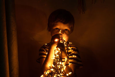 Full length of boy with illuminated lights at home