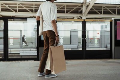 Low section of man holding bag standing at subway station