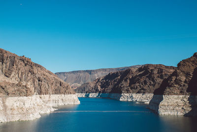 Scenic view of sea and mountains against clear blue sky