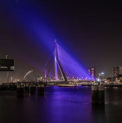 Illuminated bridge over river against sky at night