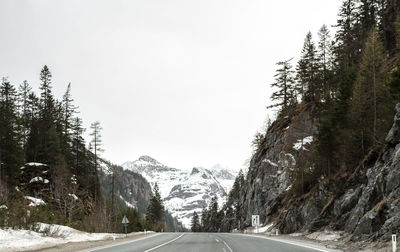 Road amidst trees against clear sky during winter