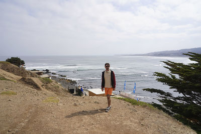 Rear view of woman walking at beach against sky