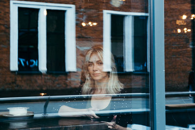 Portrait of woman looking through window