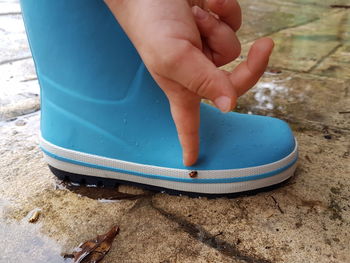 Low section of woman pointing at ladybug on rubber boot