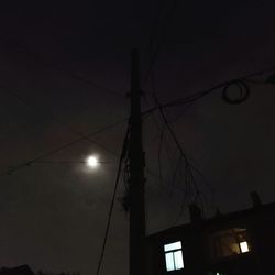 Low angle view of silhouette electricity pylon against sky at night