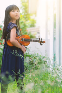 Cute girl with violin standing in park