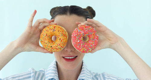 Portrait of woman holding donut against white background