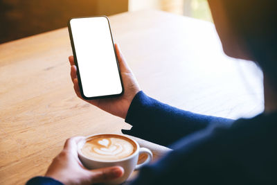 Hand holding coffee cup on table