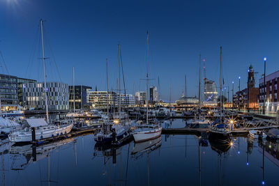 Sailboats moored at harbor against clear blue sky