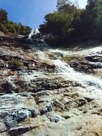 Scenic view of waterfall in forest against sky