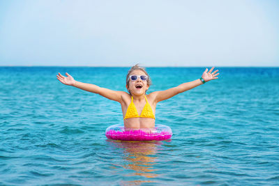 Young woman swimming in sea against sky