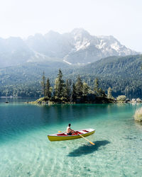 Man on boat sailing in lake by mountain
