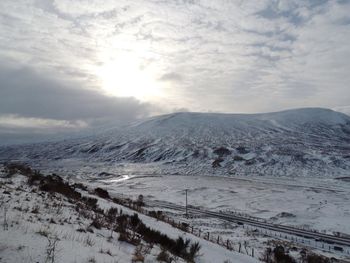 Scenic view of snow covered mountains against cloudy sky