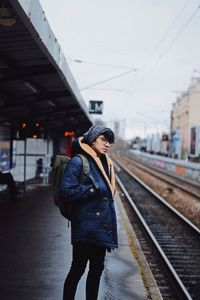 Portrait of young man standing on railroad station platform